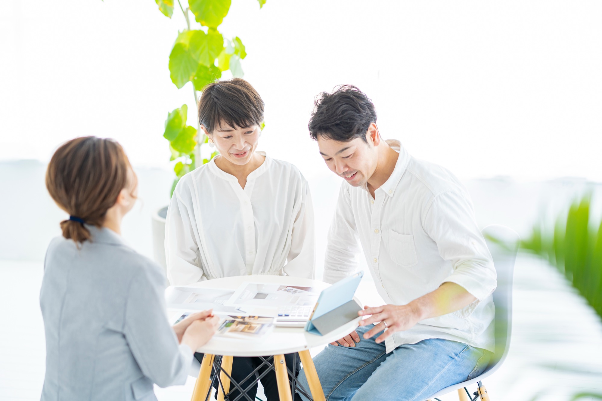 スーツ姿の女性から住宅とインテリアの説明を受ける夫婦
