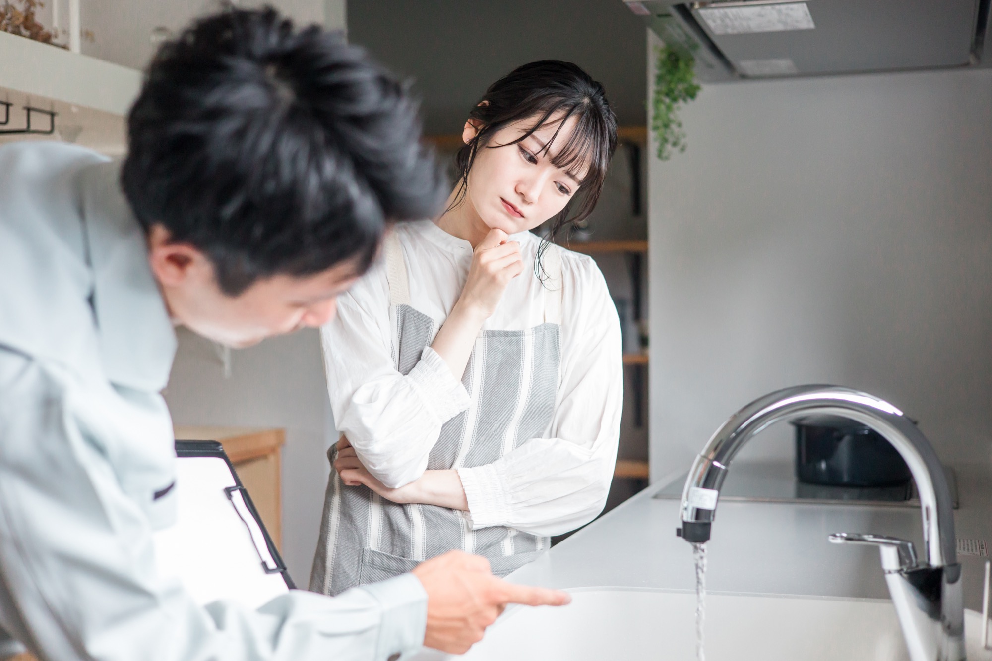 水道屋・設備屋から水道トラブル・故障・漏水・凍結・水漏れなどの説明を受ける、困っている様子の女性