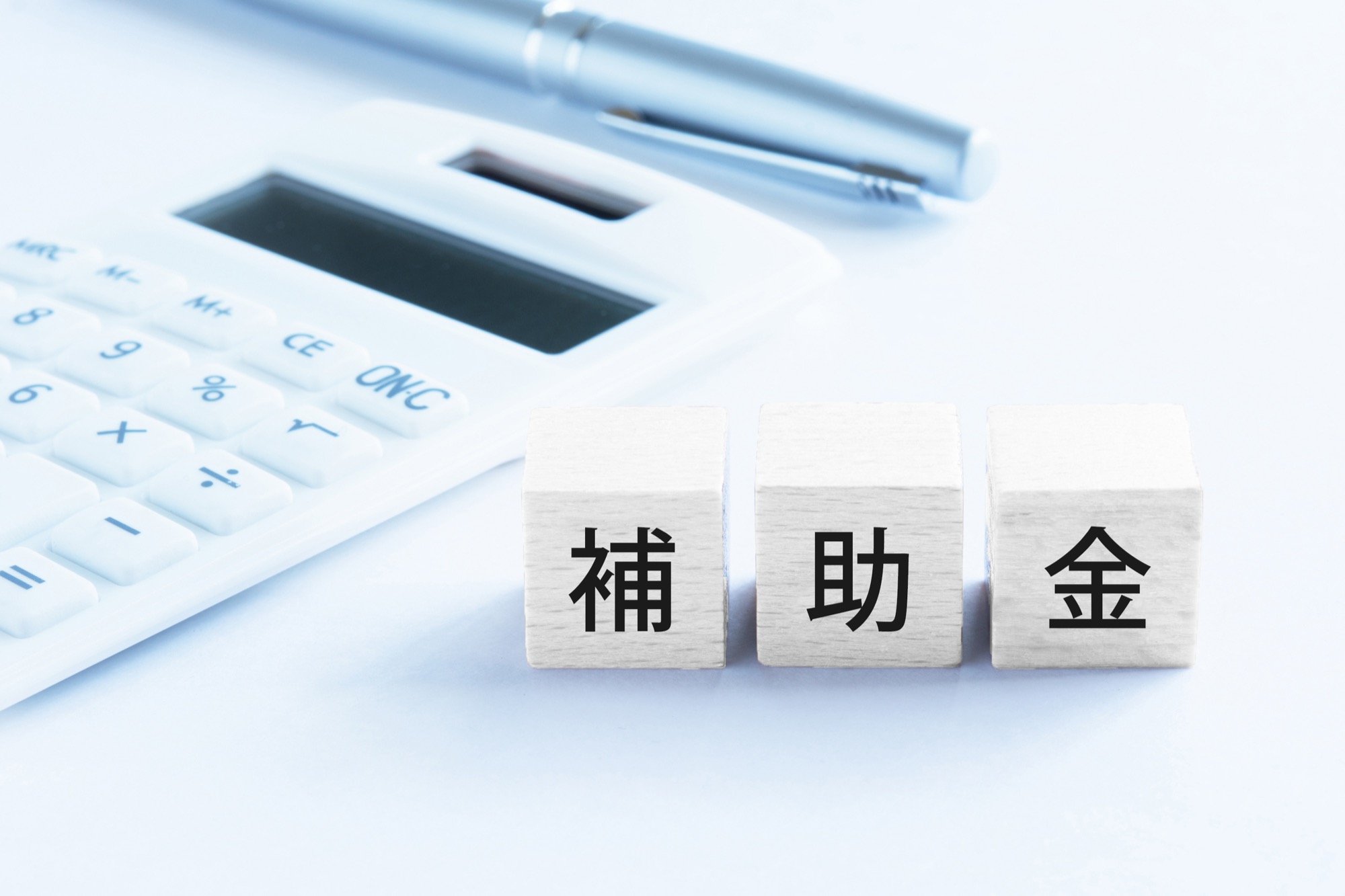 電卓と補助金と書かれたブロック